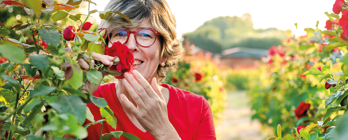 Katrin Iskam riecht an einer roten Rose im Garten