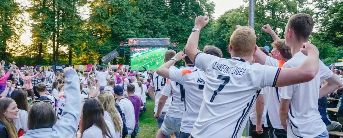 Jubelnde Fans in Fußball-Trikots beim Public Viewing